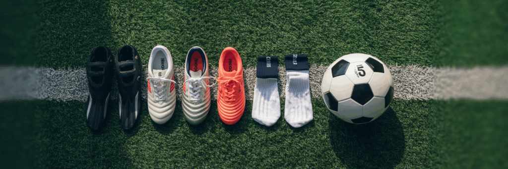 Fußball-Ausrüstung: Schuhe mit verschiedenen Sohlen, Schienbeinschützer, Stutzen und Ball.